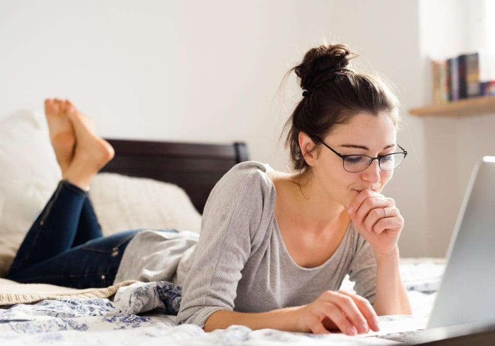 Beautiful young woman lying on bed, working. Home office. Beautiful young woman lying on bed, working on notebook, home office.