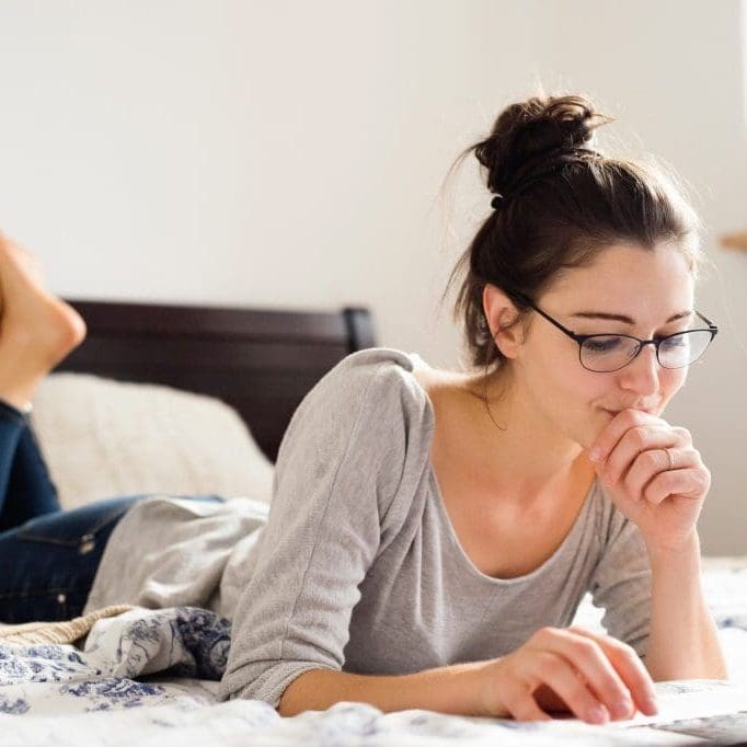 Beautiful young woman lying on bed, working. Home office. Beautiful young woman lying on bed, working on notebook, home office.