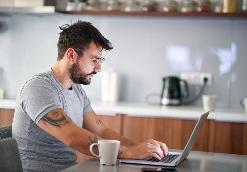 man in the morning checking email on a laptop Sleepy man in the morning checking email on a laptop