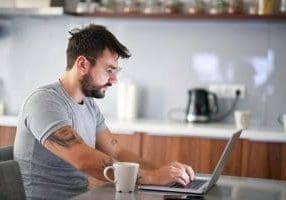 Sleepy  man  in the morning checking email on a laptop