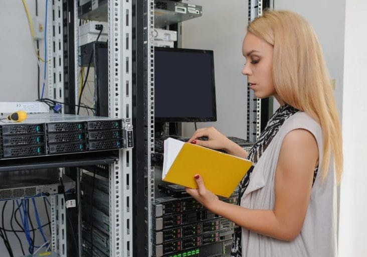 Young woman engineer It technician with notebook in the data center server room take notes about  the problem.
