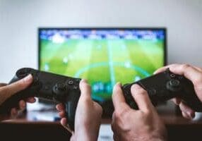 two people holding black gaming consoles